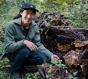 Arthur Lee crouching next to a fallen log