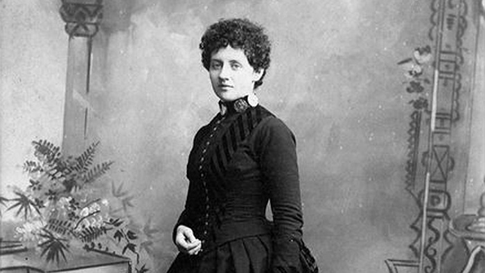 A black and white historical photograph of Laura Perrott Mahan, a white woman with dark, curly hair in a dark victorian-era dress