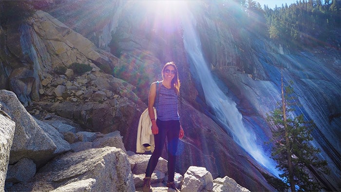 a young Chilean woman standing by a waterfall in Yosemite National Park