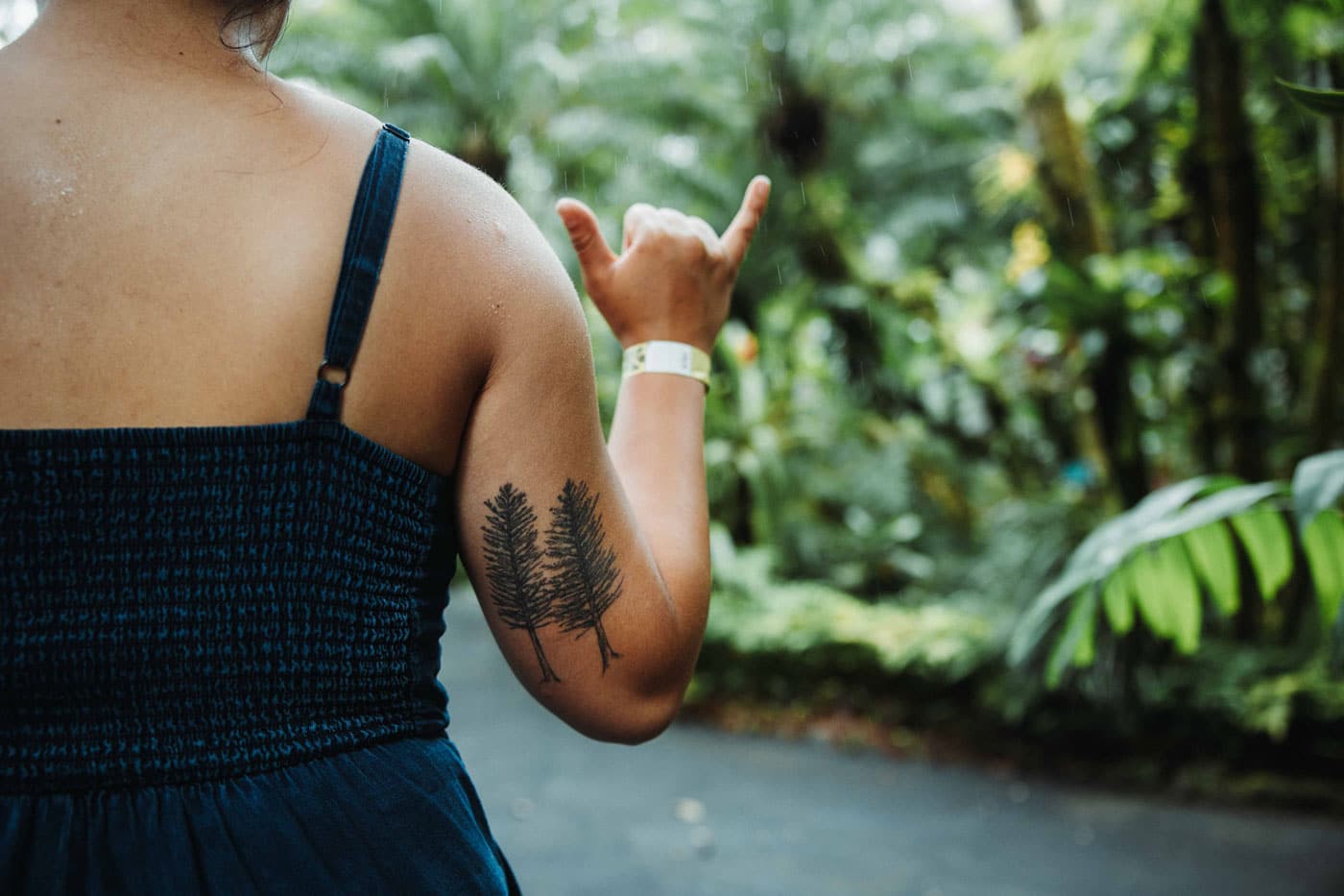 Tattoo of twin coast redwoods in black ink on the back of a woman's bicep