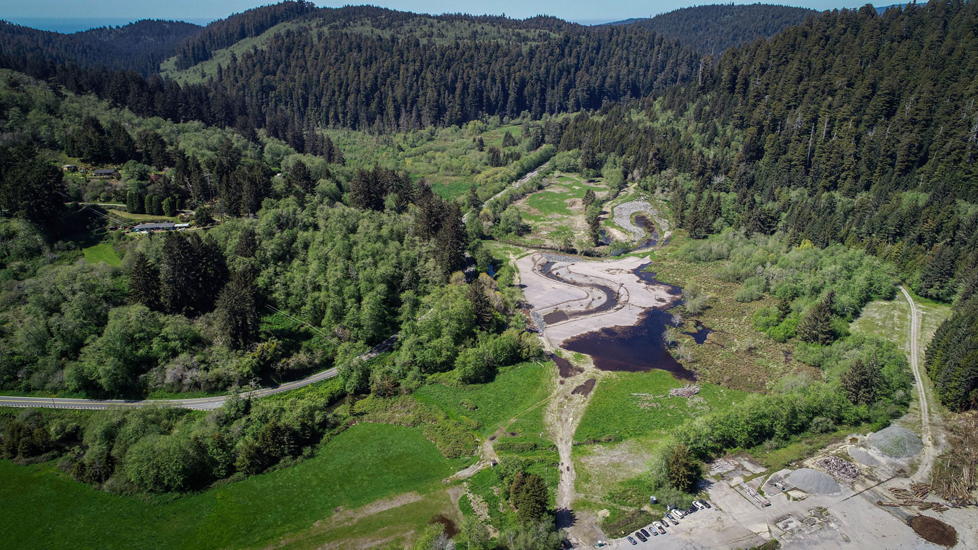 Aerial view of a floodplain, with trees and small hills surrounding the riverbank