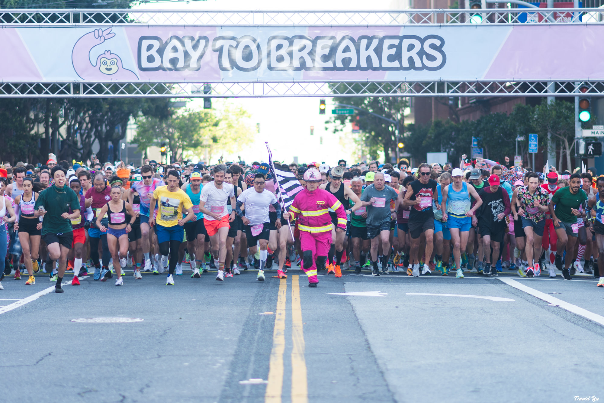 a group of runners, some in costume, prepare to start running the Bay to Breakers race
