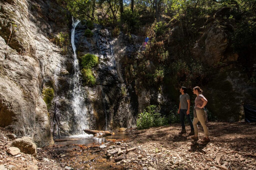 A man and woman looking up at a waterfall