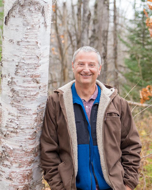 Chris Swanston leaning against a birch tree in autumn