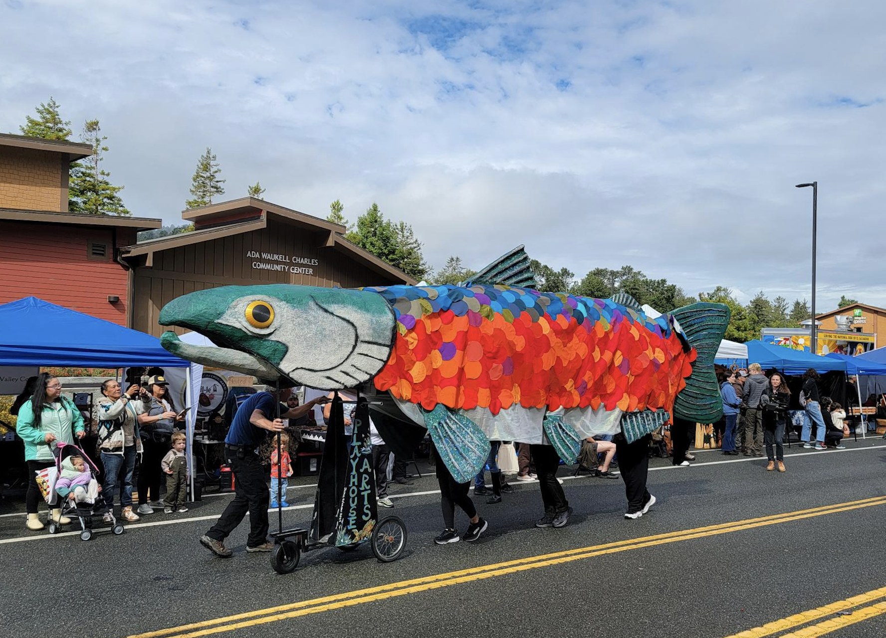 A large replica of a salmon is carried through the streets during a parade.
