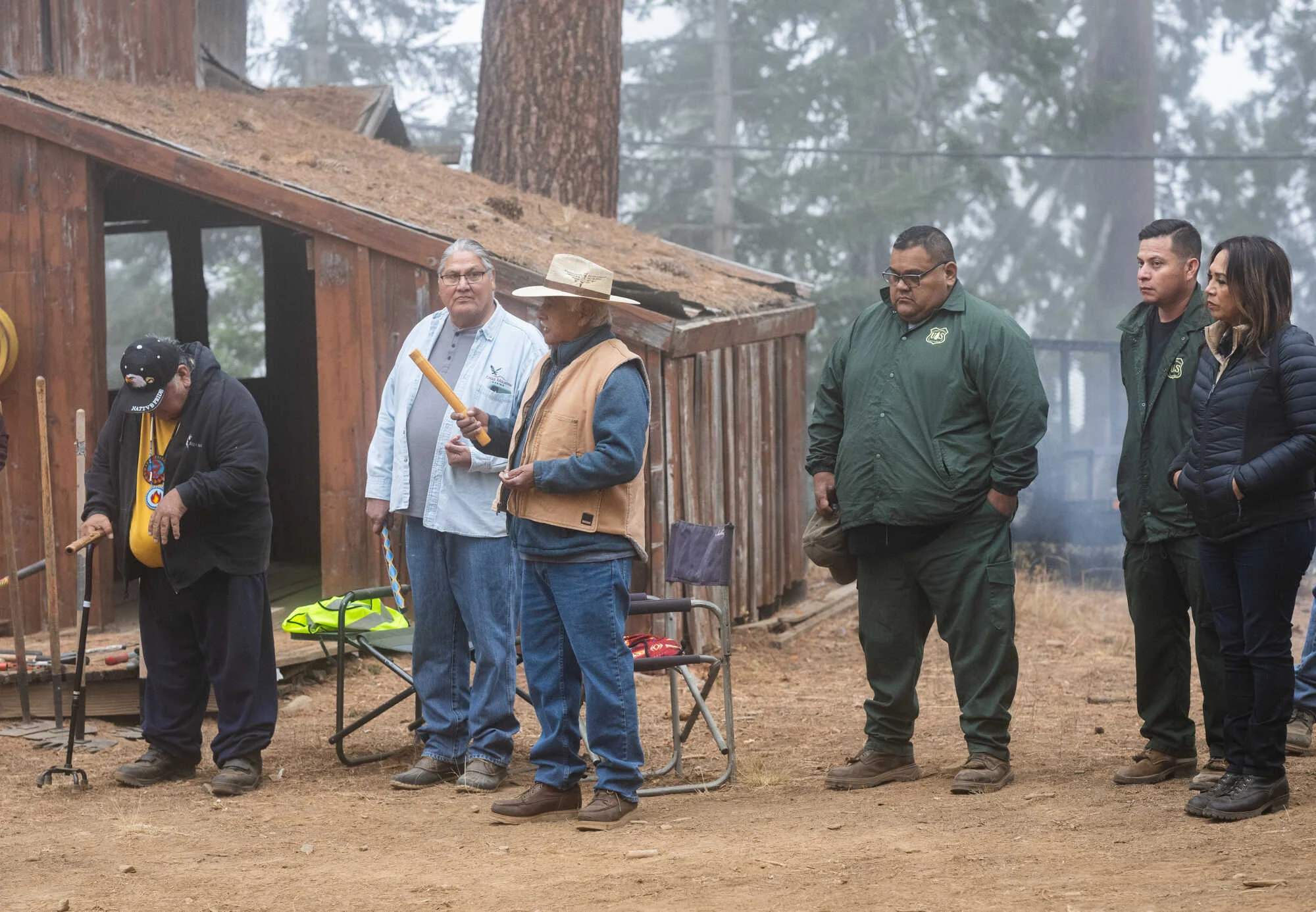Tribal members standing in front of an old barn at a cultural burn.