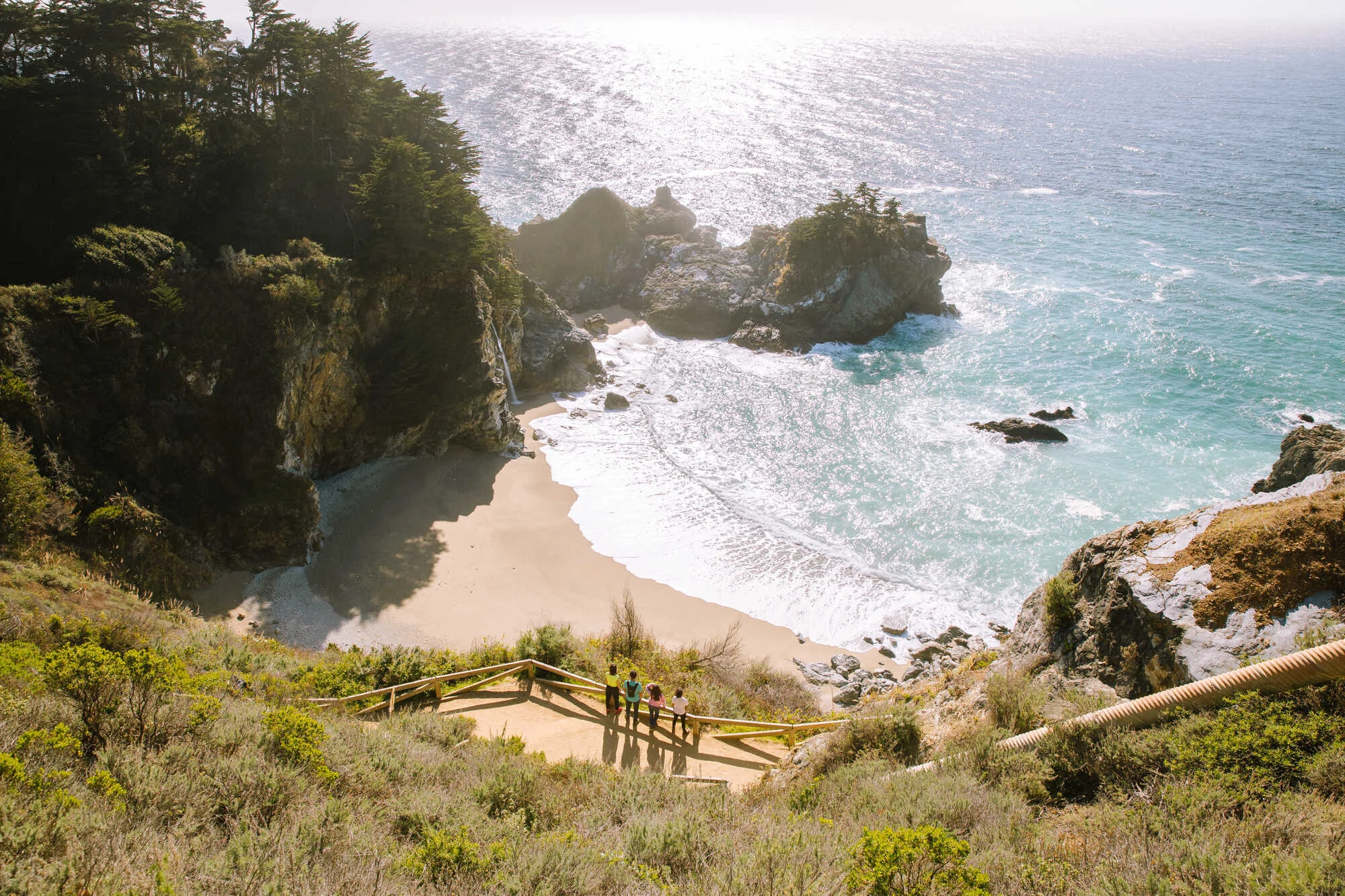 Bird's-eye view of four people overlooking a dramatic coastal beach