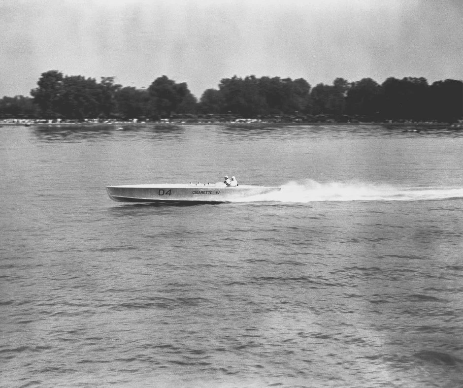 Black and white photograph of a motor boat speeding across the water.