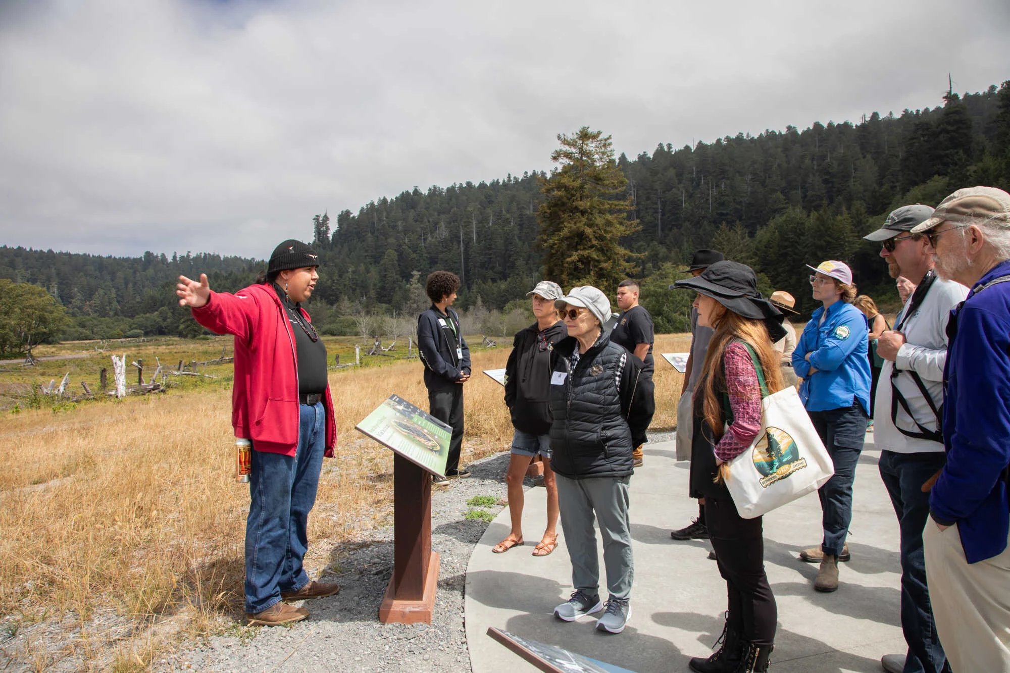Indigenous man in red hoodie and black beanie giving tour