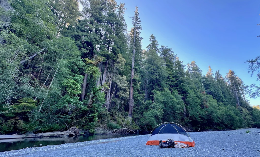 a backpacking tent on a gravel bar next to a creek