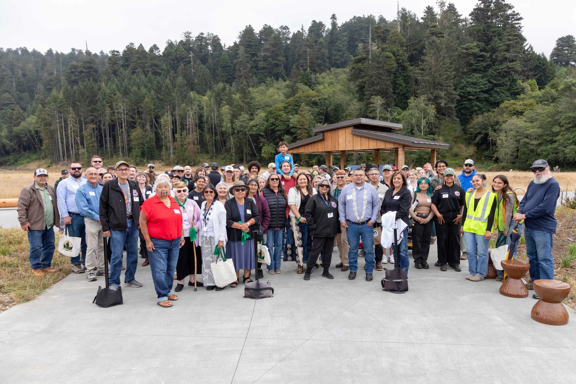 A group of Yurok Tribal members cutting a green ribbon ribbon in front of the new gateway on opening day.